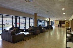 A spacious lobby with leather seating, large windows, and a view of the parking area. - Alda El Espinar (El Espinar)