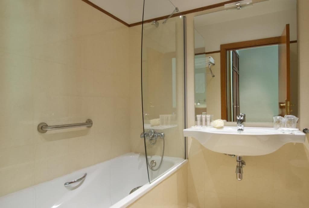 A modern bathroom with a glass-enclosed shower, a white bathtub, and a vanity with a mirror and sink.