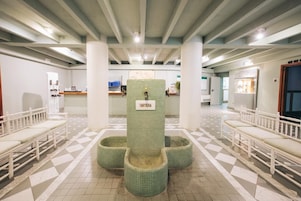 Zona de recepción con piso de baldosas, bancos blancos y un pilar central con la etiqueta "TARTERA".