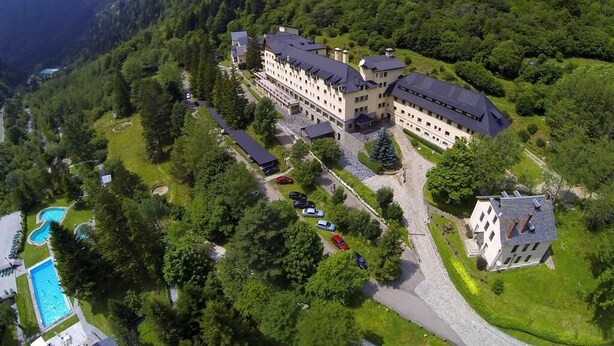Un grand hôtel composé de plusieurs bâtiments, entouré d’une végétation luxuriante et de montagnes.