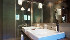 Une salle de bain moderne avec deux vasques, une douche à l’italienne en verre et un grand miroir.