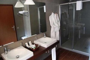 Une salle de bain moderne avec deux vasques, une douche à l’italienne en verre et un grand miroir.