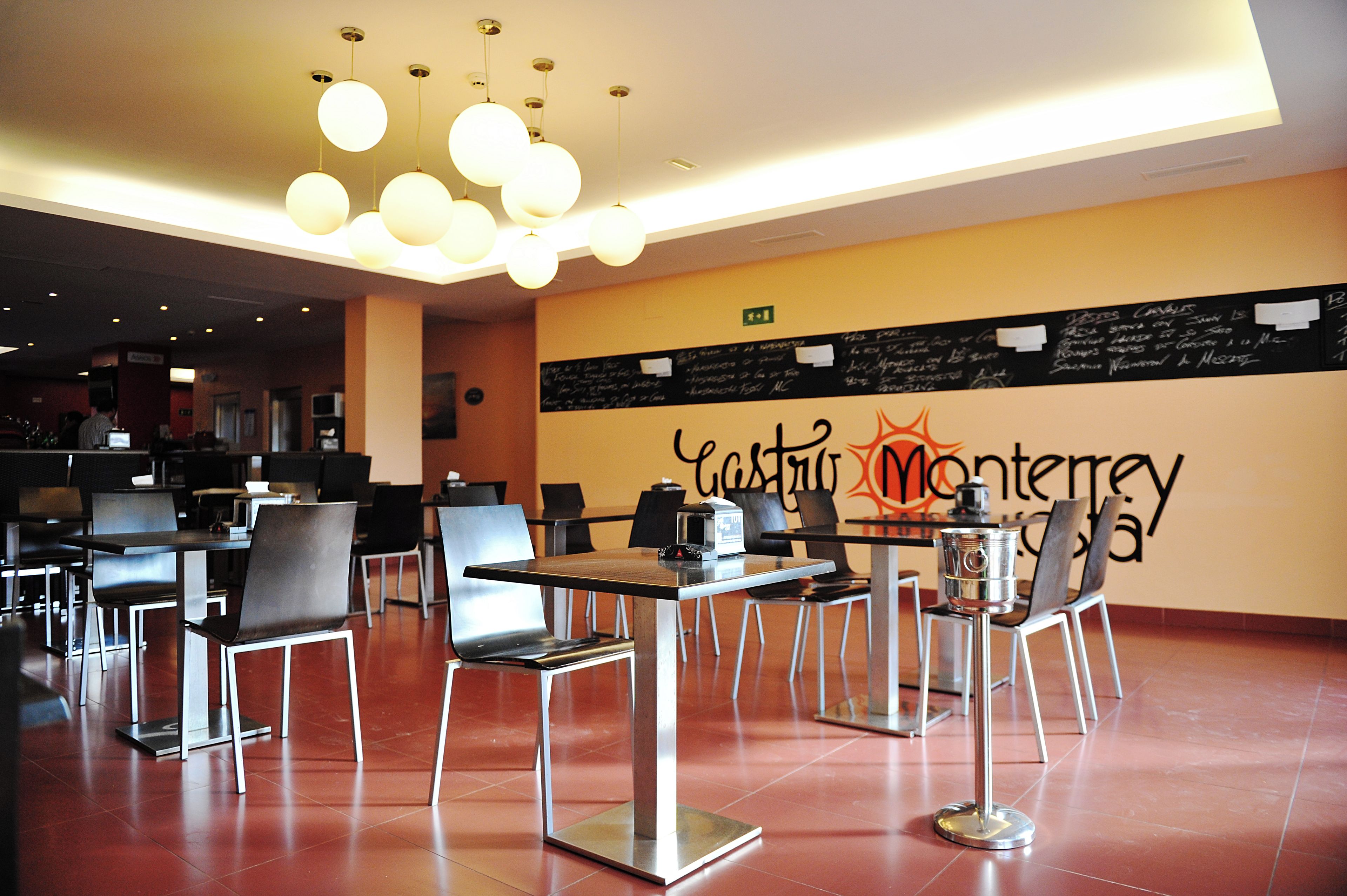 A restaurant with a modern interior, featuring tables and chairs arranged for dining.