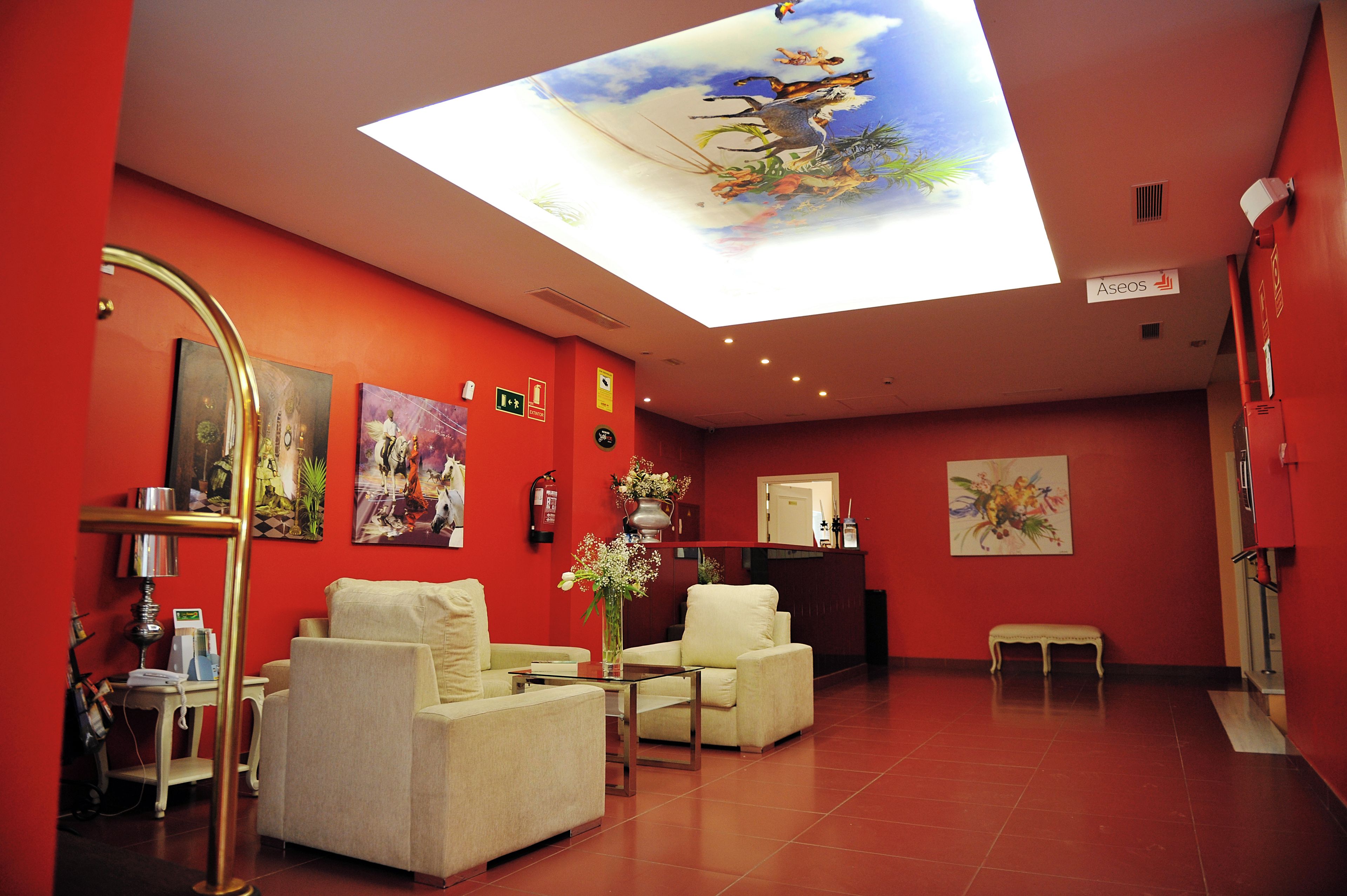 A hotel lobby with red walls, a reception desk, and a ceiling skylight.