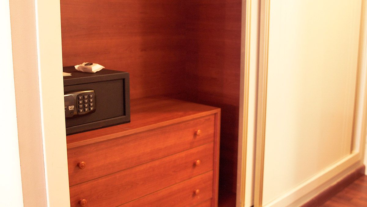 A wooden chest of drawers with a black safe on top.