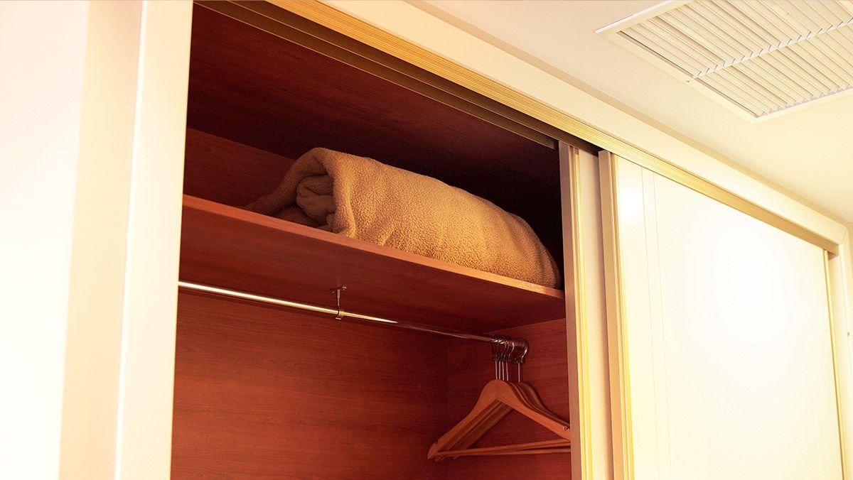 A closet with a hanging rod and a shelf.