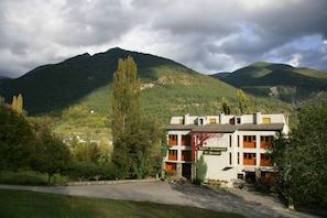 A hotel with a sign reading "Hotel Restaurante El Mirador" in a mountainous area with lush greenery and a cloudy sky. - El Mirador (Puertolas)
