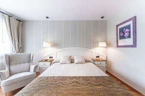 A bedroom with a large bed, two bedside tables, a chair, and a wall-mounted picture. - El Mirador (Puertolas)