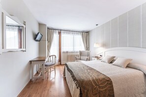 A hotel room with a bed, a desk, a chair, a TV, and a window with curtains. - El Mirador (Puertolas)