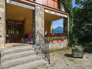 A restaurant with outdoor seating, stone steps, and a view of a mountain. - El Mirador (Puertolas)
