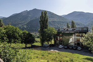 A hotel with a parking lot, surrounded by greenery and mountains in the background. - El Mirador (Puertolas)
