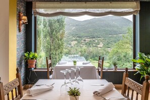 A dining table set for four with a scenic mountain view, a potted plant, and a lamp on the wall. - El Mirador (Puertolas)