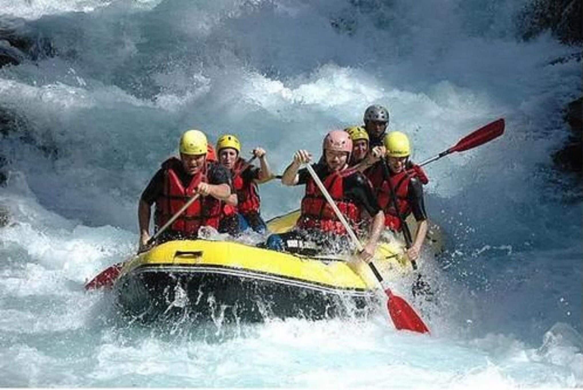 Un grupo de personas en un bote amarillo navegando por un río con rápidos.