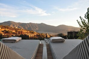 Terraço no telhado com cadeiras de descanso e vista para as montanhas.
