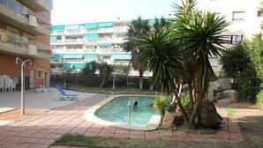 Zona de piscina con jacuzzi, sillas de descanso y palmeras.