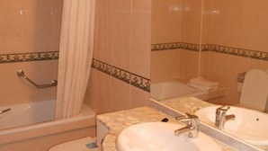 Un baño con bañera, dos lavamanos y un espejo.