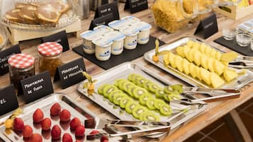 Ein reichhaltiges Buffet mit einer Auswahl an Speisen, darunter Obst, Gebäck und Getränke.