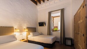 A hotel room with two beds, a television, a small table, and a wardrobe. - Convento de San Francisco (Vejer de la Frontera)