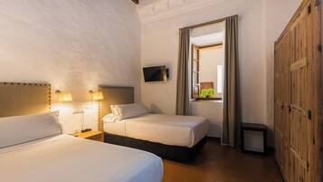 A hotel room with two beds, a television, a small table, and a wardrobe.