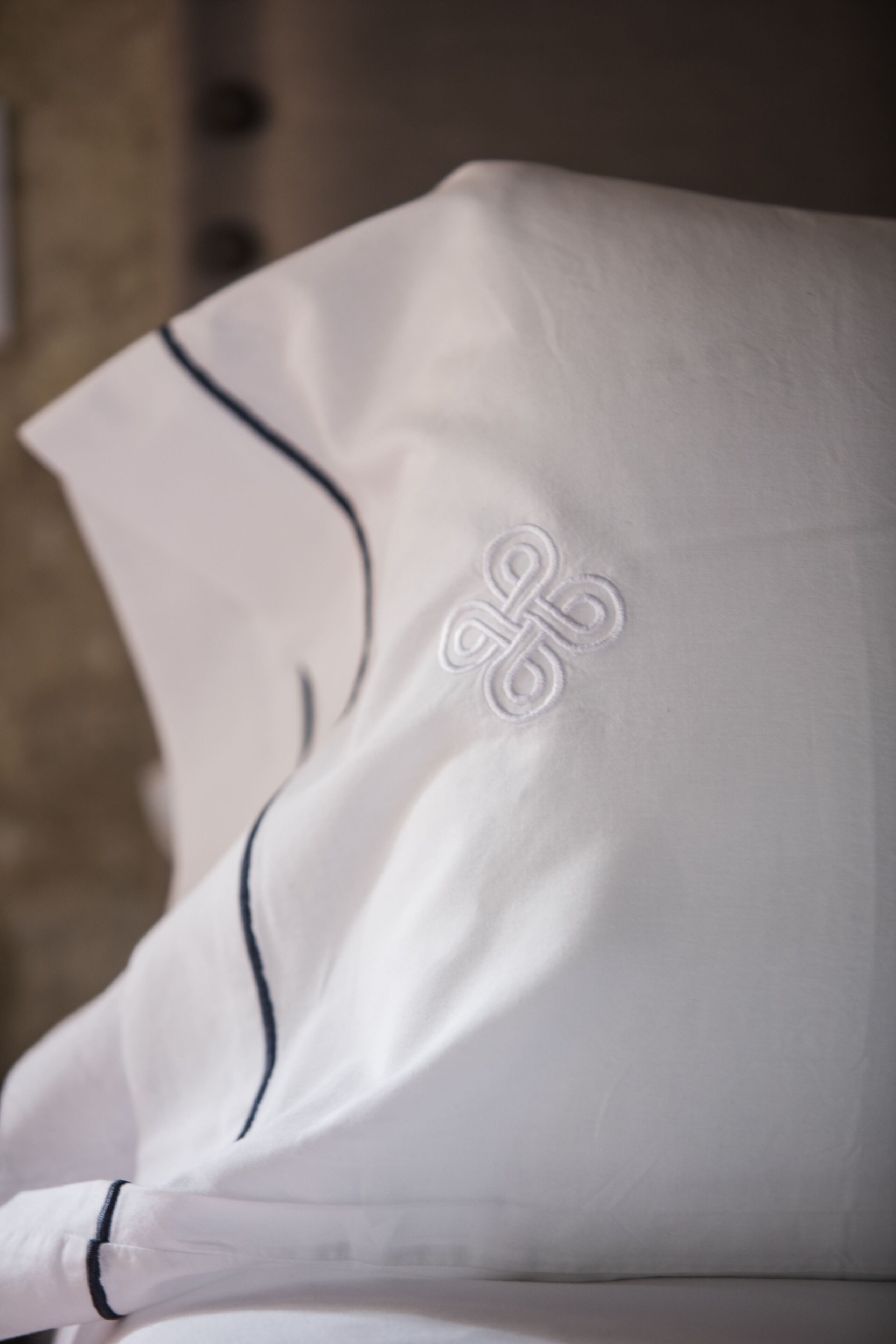 A white pillow with a monogram embroidery.