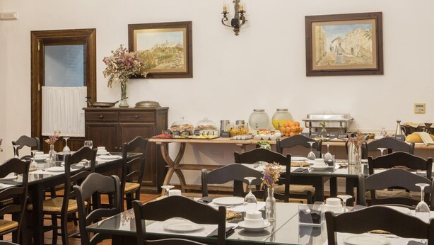 A dining area with tables set for meals, a chandelier, and artwork on the walls. - Convento de San Francisco (Vejer de la Frontera)