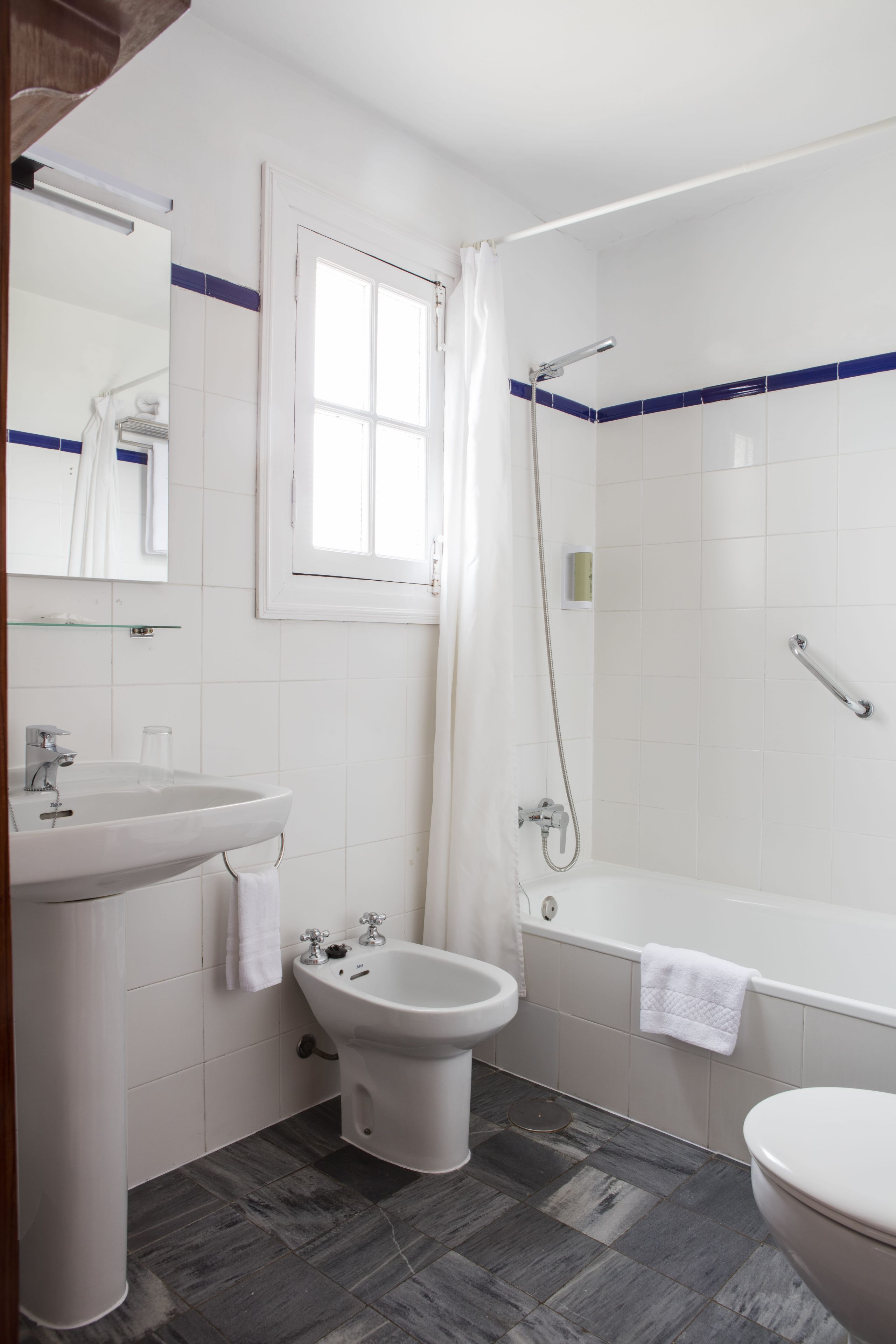 A bathroom with a sink, bidet, toilet, and bathtub.