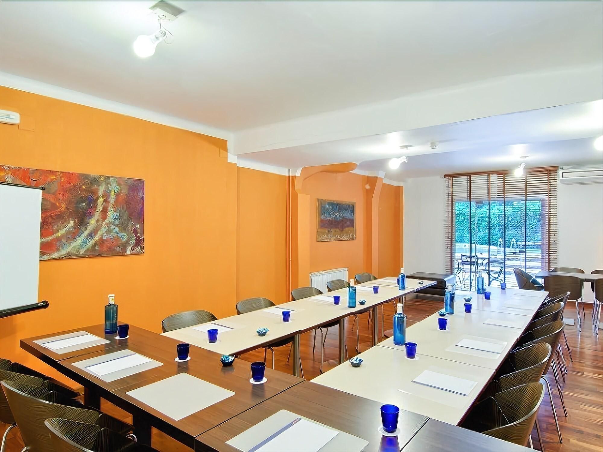 Una sala de conferencias con una mesa larga, sillas y una pizarra.