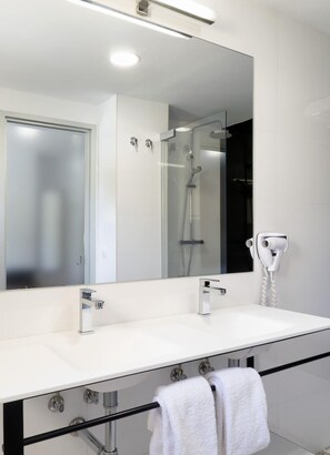 A modern bathroom with a large mirror, two sinks, a shower, and a hairdryer. - Aatu (Forallac)