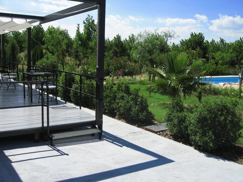 An outdoor deck with tables and chairs, overlooking a swimming pool and lush greenery.