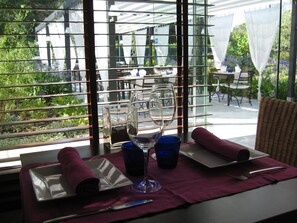 A table set for dining with a view of an outdoor garden through a glass partition. - Aatu (Forallac)