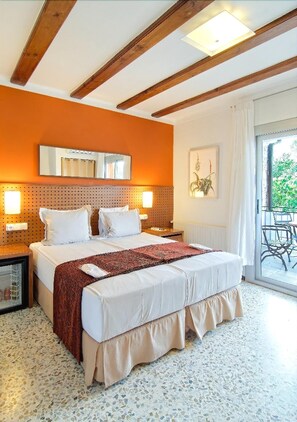 A bedroom with a large bed, wooden beams, a ceiling light, a window with a view, and a small table with a chair. - Aatu (Forallac)