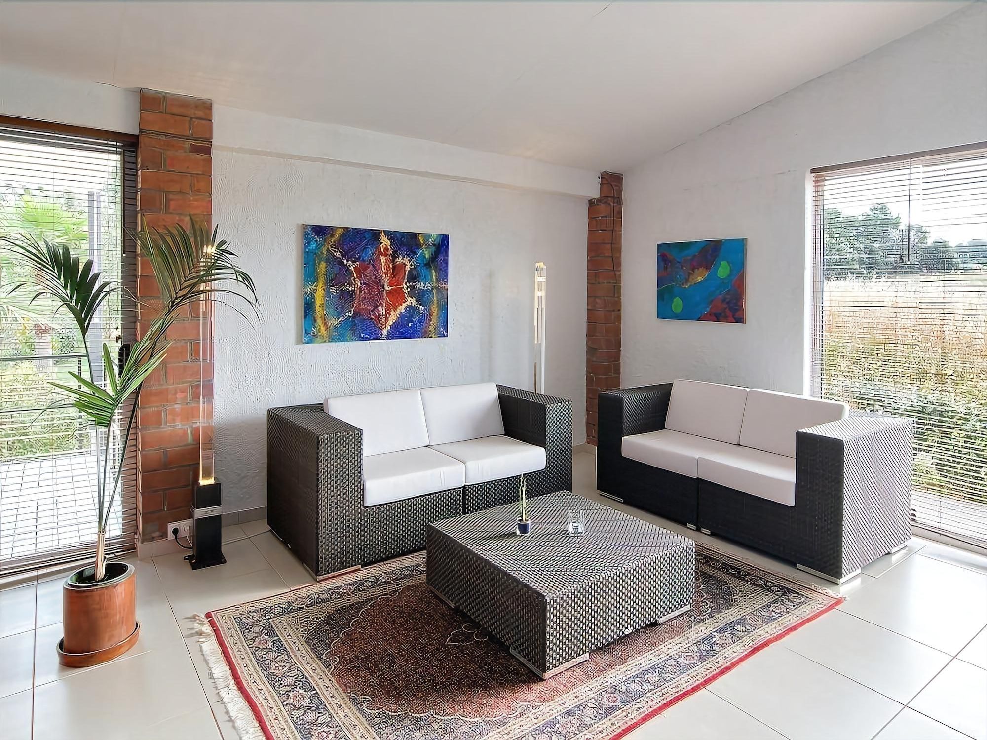 Una sala moderna con dos sofás, una mesa de centro y un cuadro abstracto grande en la pared.