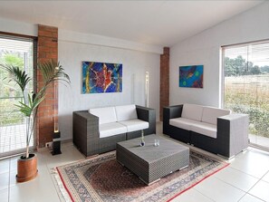 A modern living room with two sofas, a coffee table, and a large abstract painting on the wall. - Aatu (Forallac)