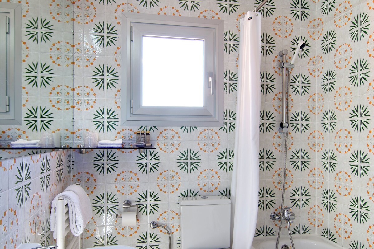 A bathroom with a sink, toilet, and bathtub, all with a floral tile pattern.