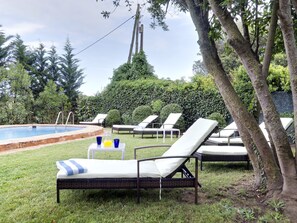 A poolside area with lounge chairs and a small table with drinks. - Aatu (Forallac)