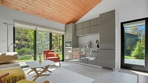 Un interior moderno con cocina, comedor y amplios ventanales que dan a zonas verdes.