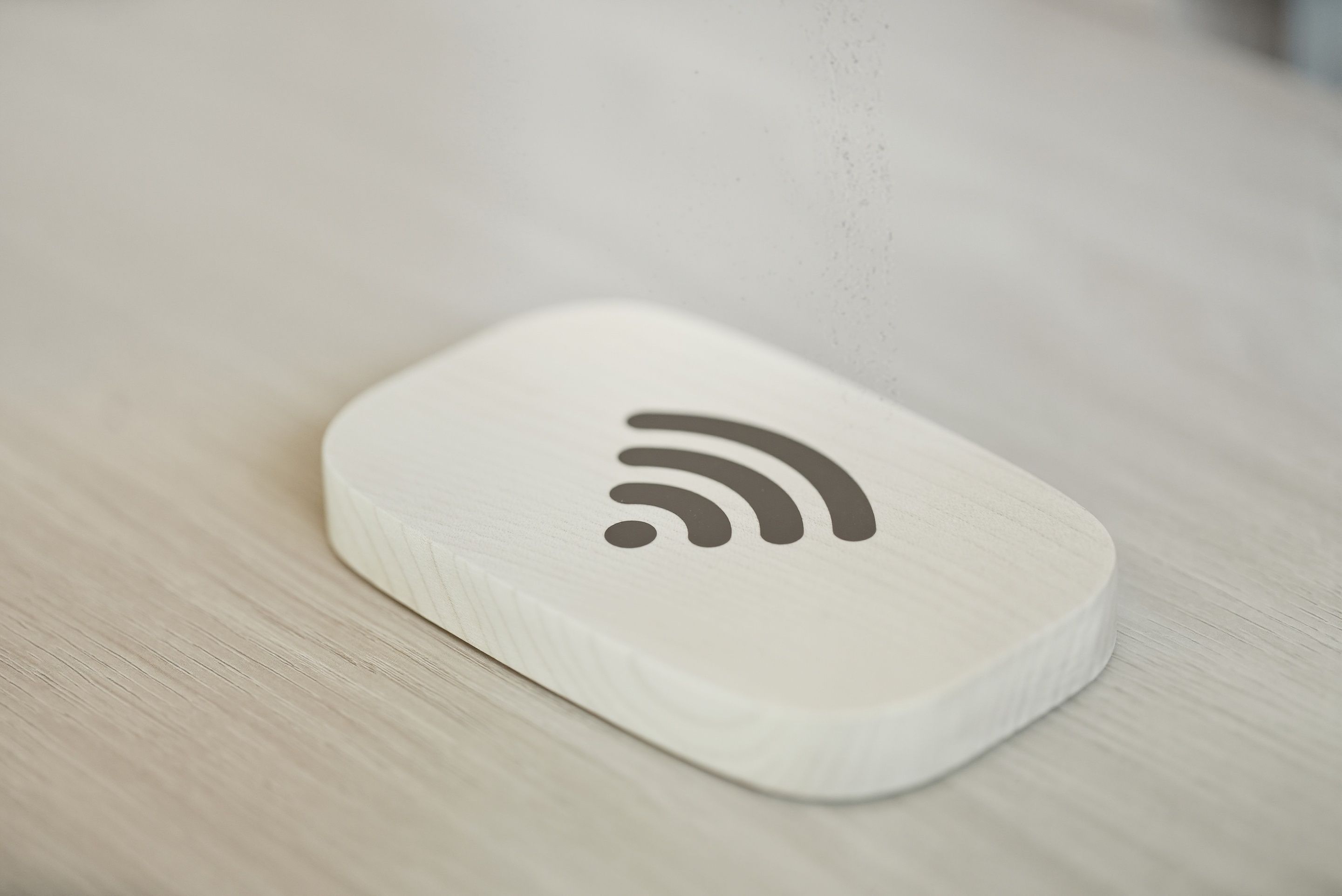 A white, rectangular object with a Wi-Fi symbol on a wooden surface.