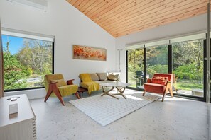 A modern living room with a sofa, armchairs, a coffee table, and a painting. - Loft 1 - Designer Cabin, Walls of Light, Sauna (West Windsor)