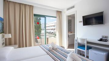 Une chambre d’hôtel équipée d’un lit, d’un bureau, d’une télévision et offrant une vue sur l’extérieur.