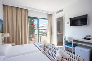 A hotel room with a bed, a desk, a television, and a view of the outside. - Hotel Rosales Formentera (Formentera)