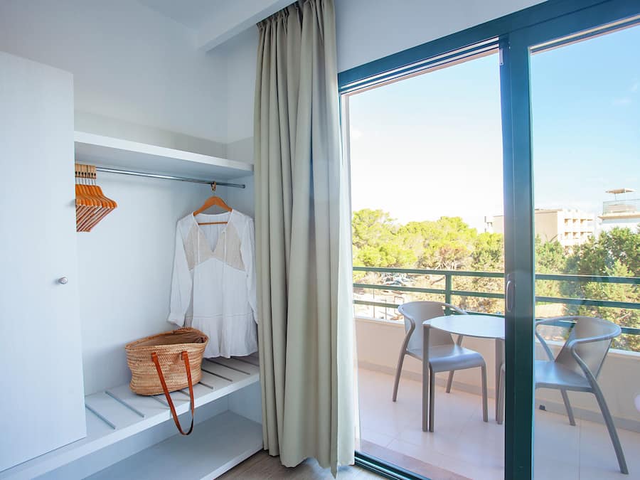 A balcony with a table and chairs, a hanging basket, and a white shirt on a hanger.