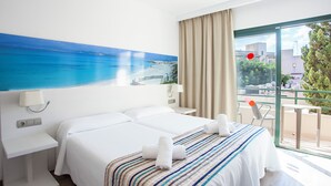 Ein Hotelzimmer mit Bett, Schreibtisch, Lampe, einem fenster mit Vorhängen und Meerblick.