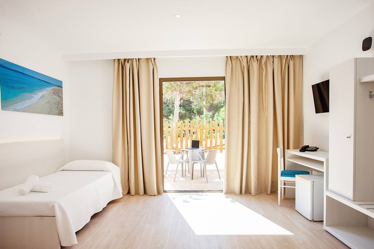 Une chambre d’hôtel équipée d’un lit, d’un bureau, d’une chaise, d’une télévision et offrant une vue sur l’extérieur.