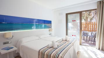 Habitación de hotel con dos camas, un ventanal con vistas al mar y un balcón con mobiliario exterior.
