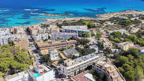 Luftaufnahme einer Küstenstadt mit Häusern, einem Strand und klarem, blauem Wasser.