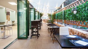 A modern indoor dining area with glass partitions, wooden tables, and chairs. - Hotel Rosales Formentera (Formentera)