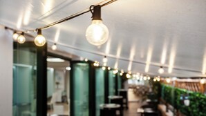 Ein Korridor mit hängenden Lampen, Glastrennwänden und Tischen.