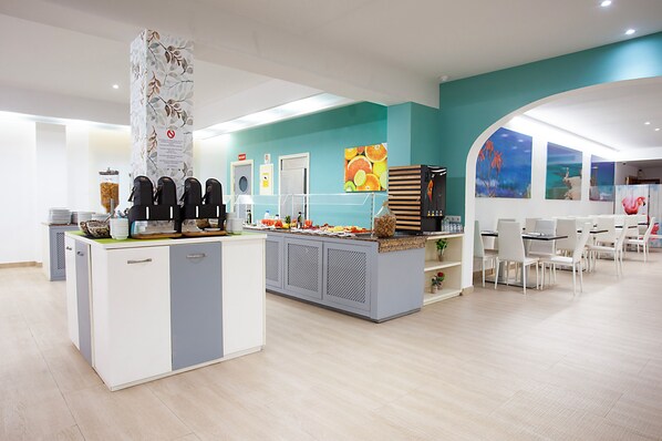 A modern cafe with a central counter, seating area, and artwork on the walls. - Hotel Rosales Formentera (Formentera)