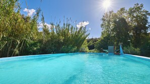 A clear blue swimming pool surrounded by lush greenery and trees. - Mas Torrencito (Vilademuls)
