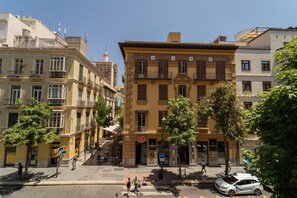 Un bâtiment historique doté d’une entrée centrale, de plusieurs balcons et d’un café situé au rez-de-chaussée.